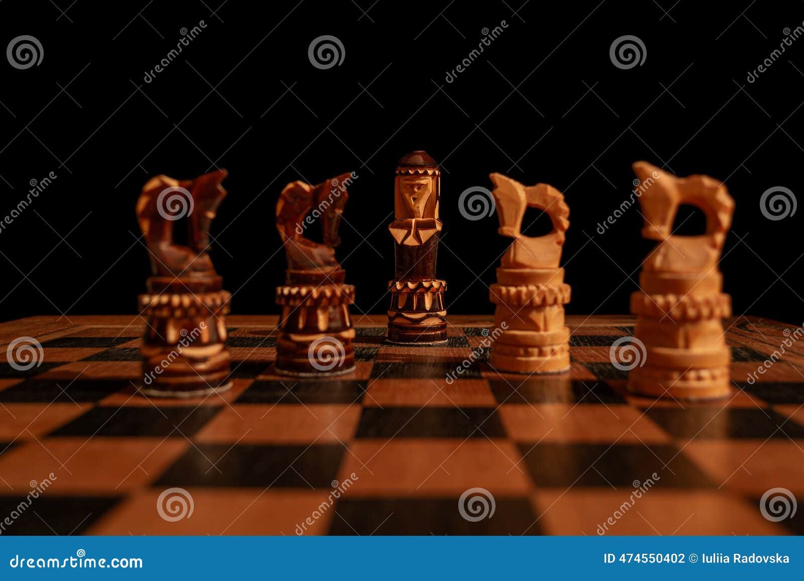 A wooden chessboard mid-game in dramatic side light